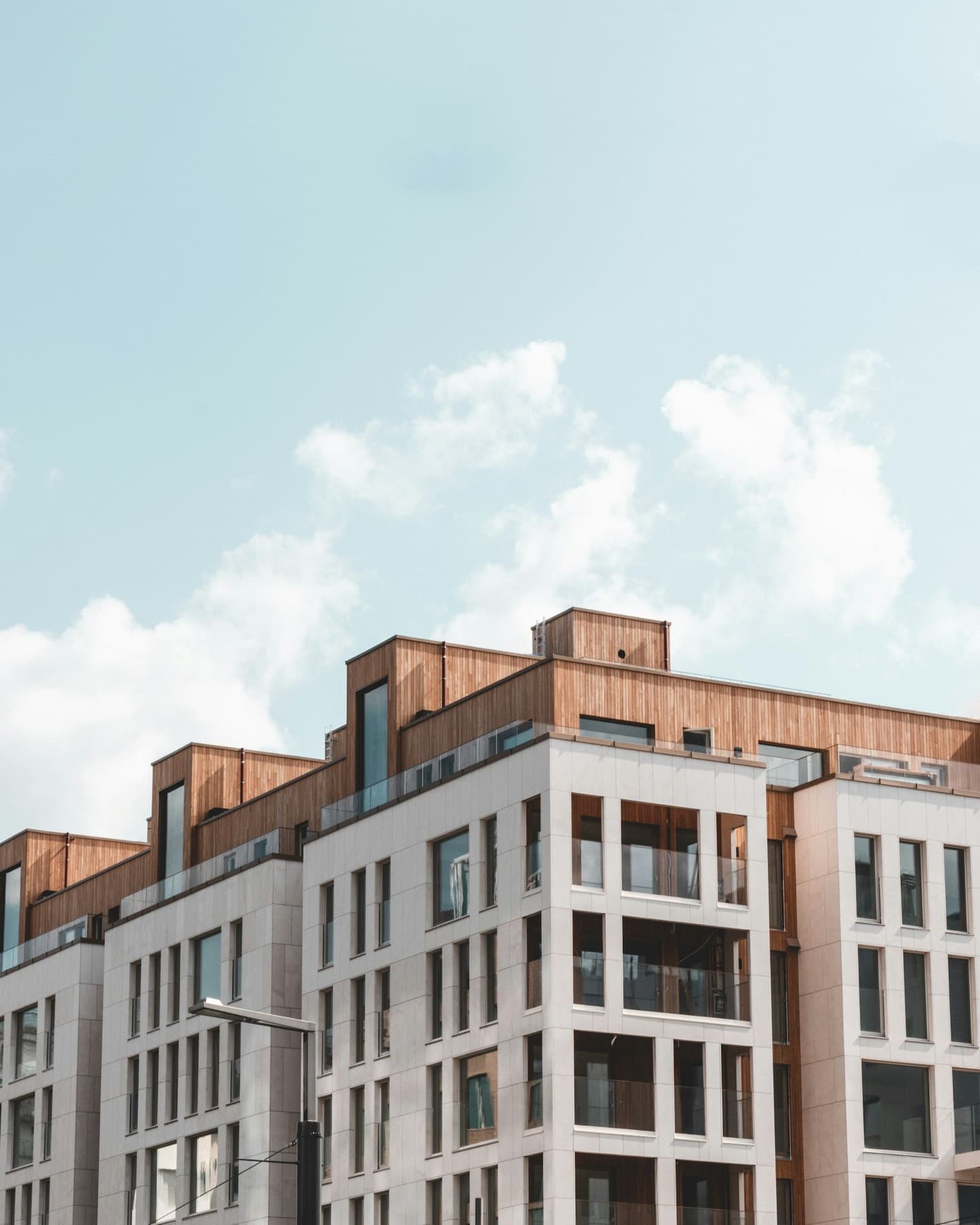 A row of apartment blocks with timber-clad top floors under a pale sky